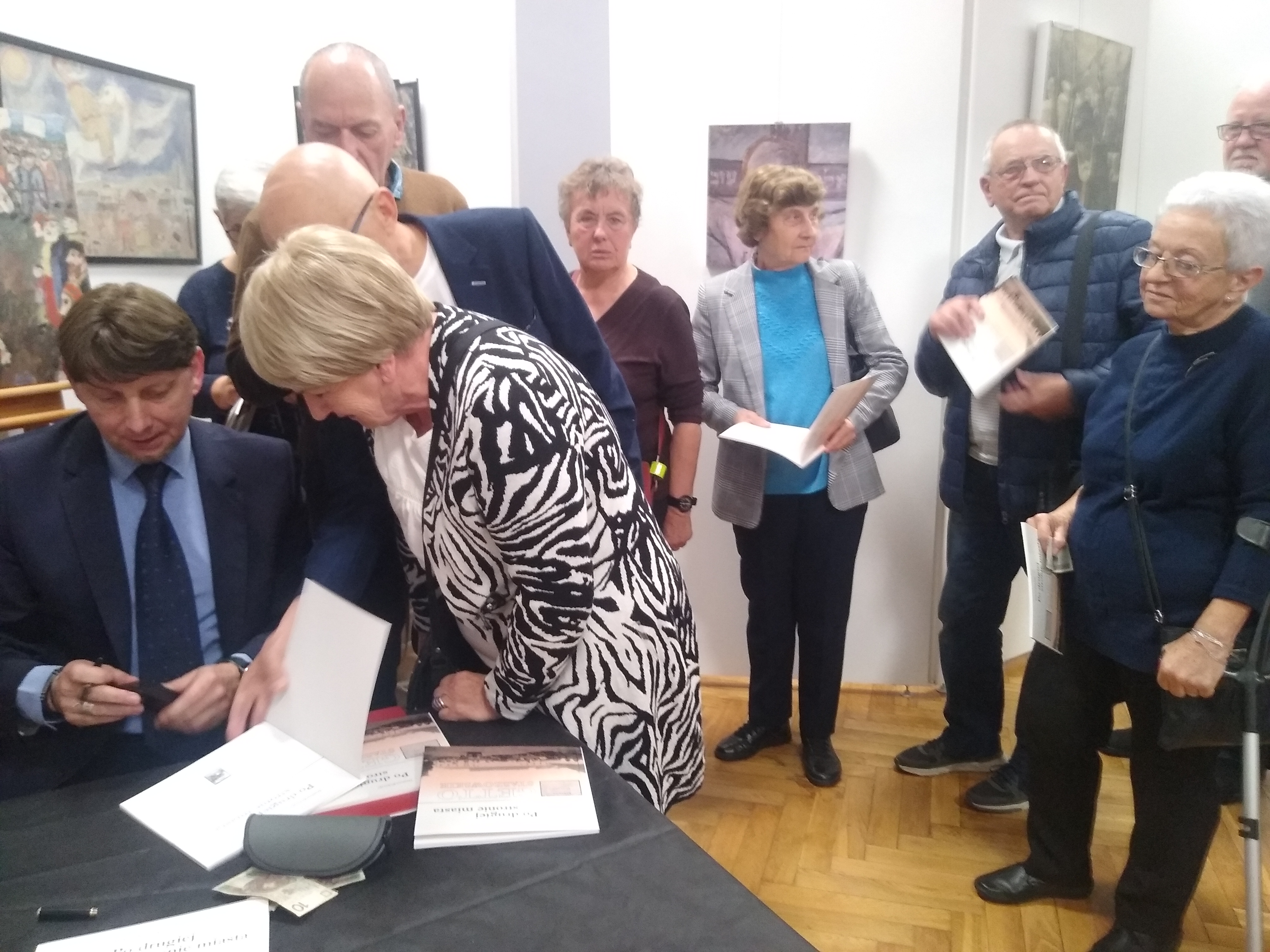 Autor książki podpisuje swoją publikację w otoczeniu czytelników
