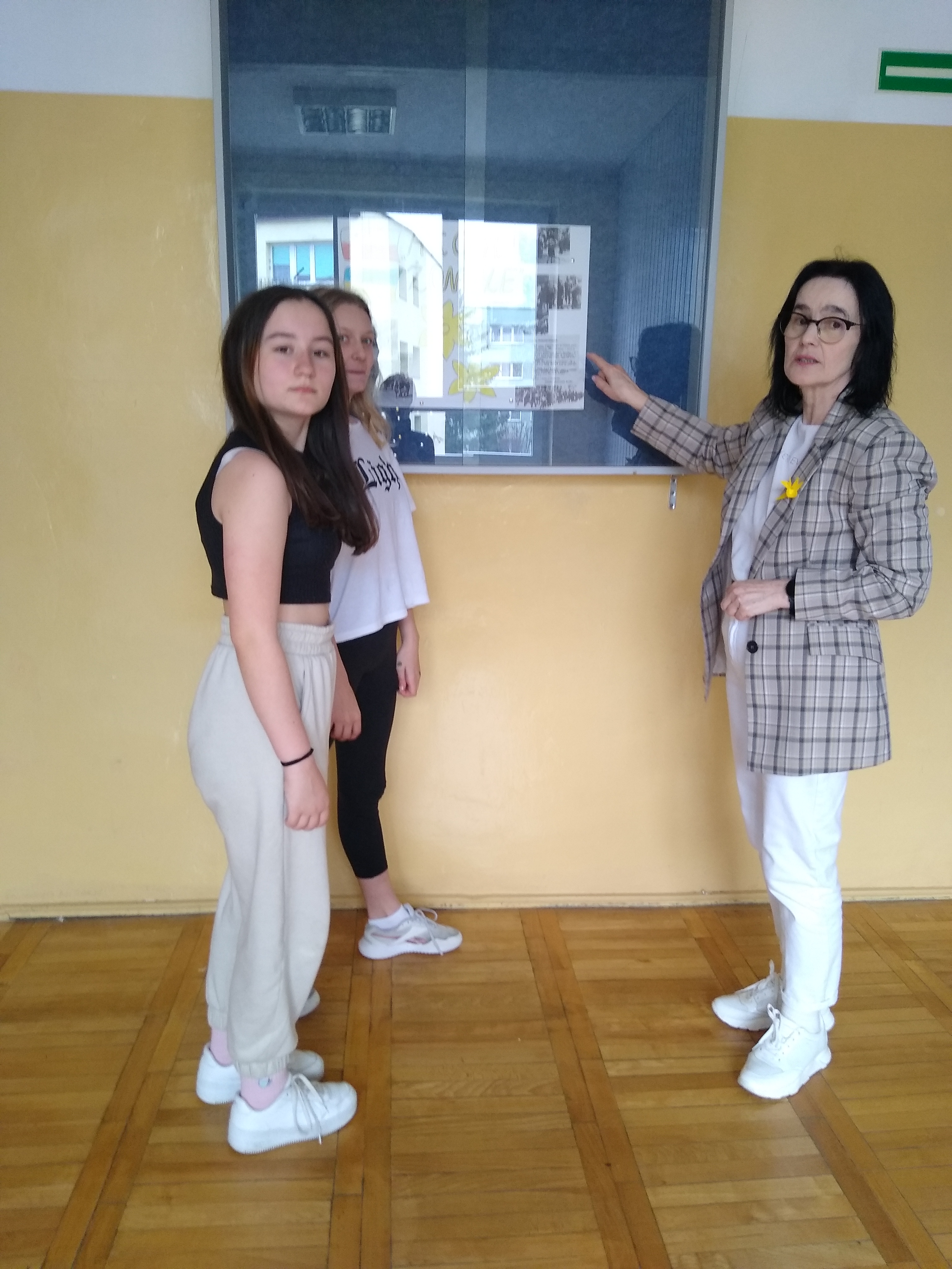 Nauczycielka omawia z uczennicami klasy piątej plakat akcji 