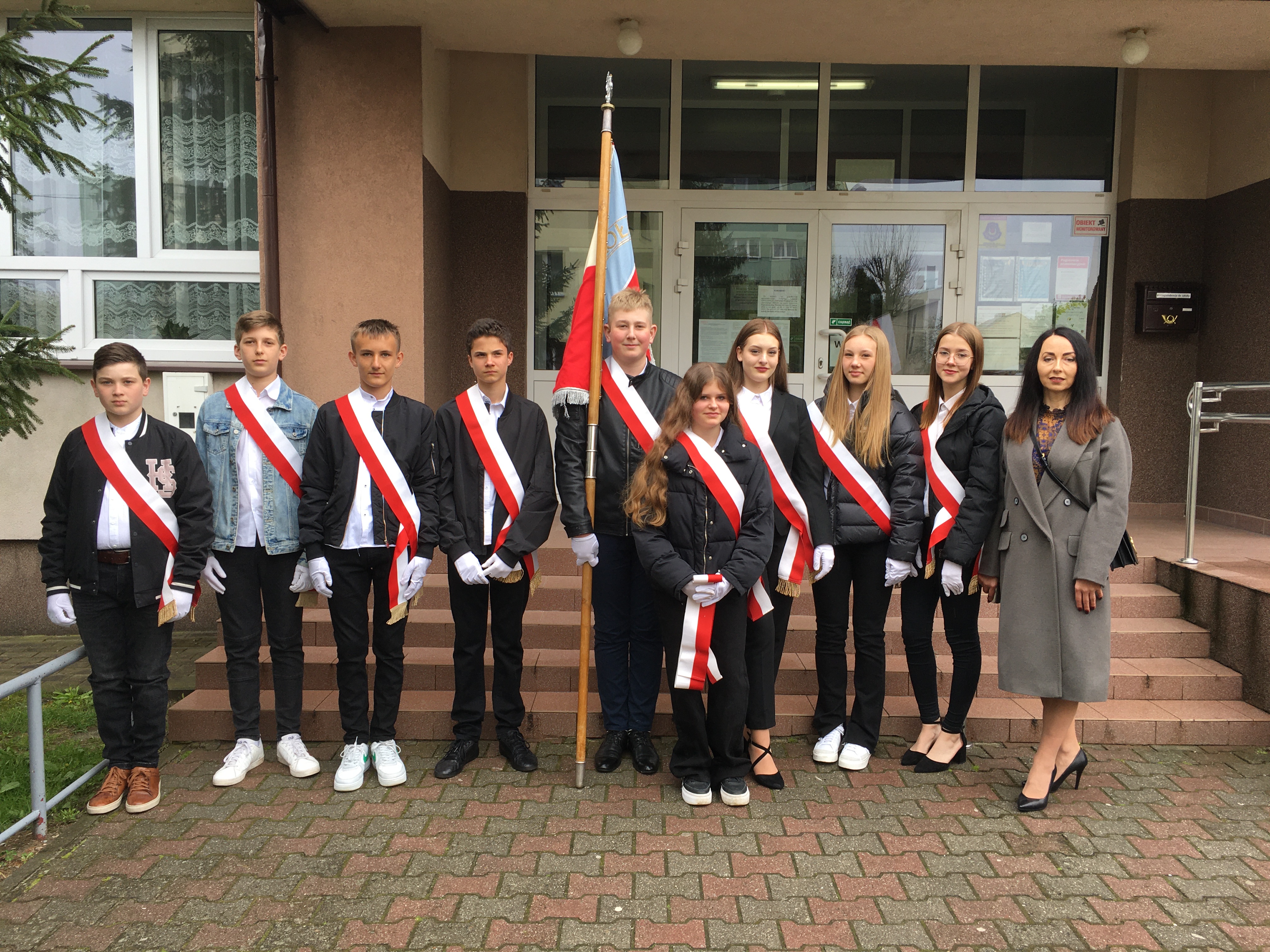 Poczty sztandarowe z opiekunem przed szkołą