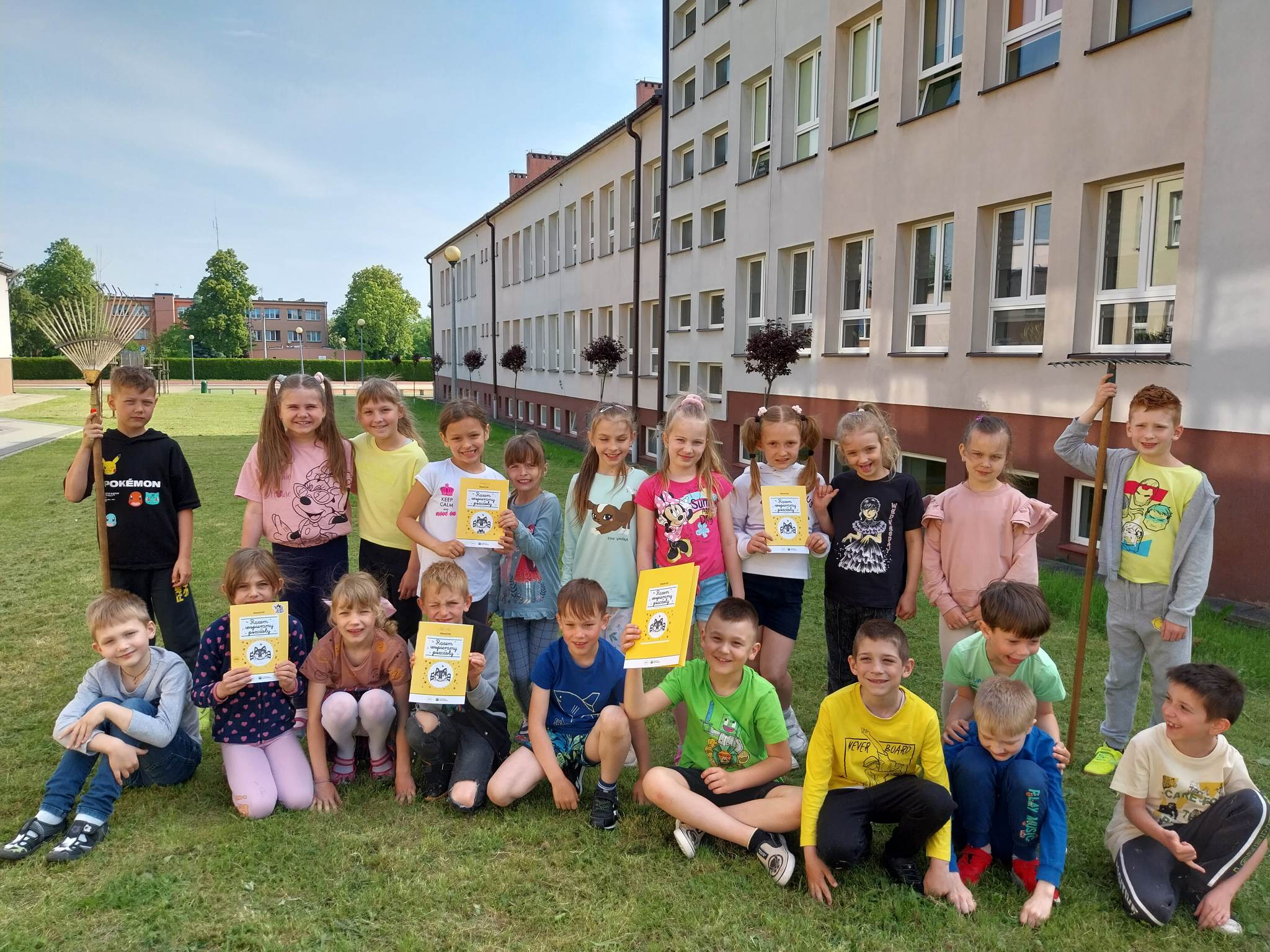 Zdjęcie grupowe – dzieci na trawniku z pakietami edukacyjnymi
