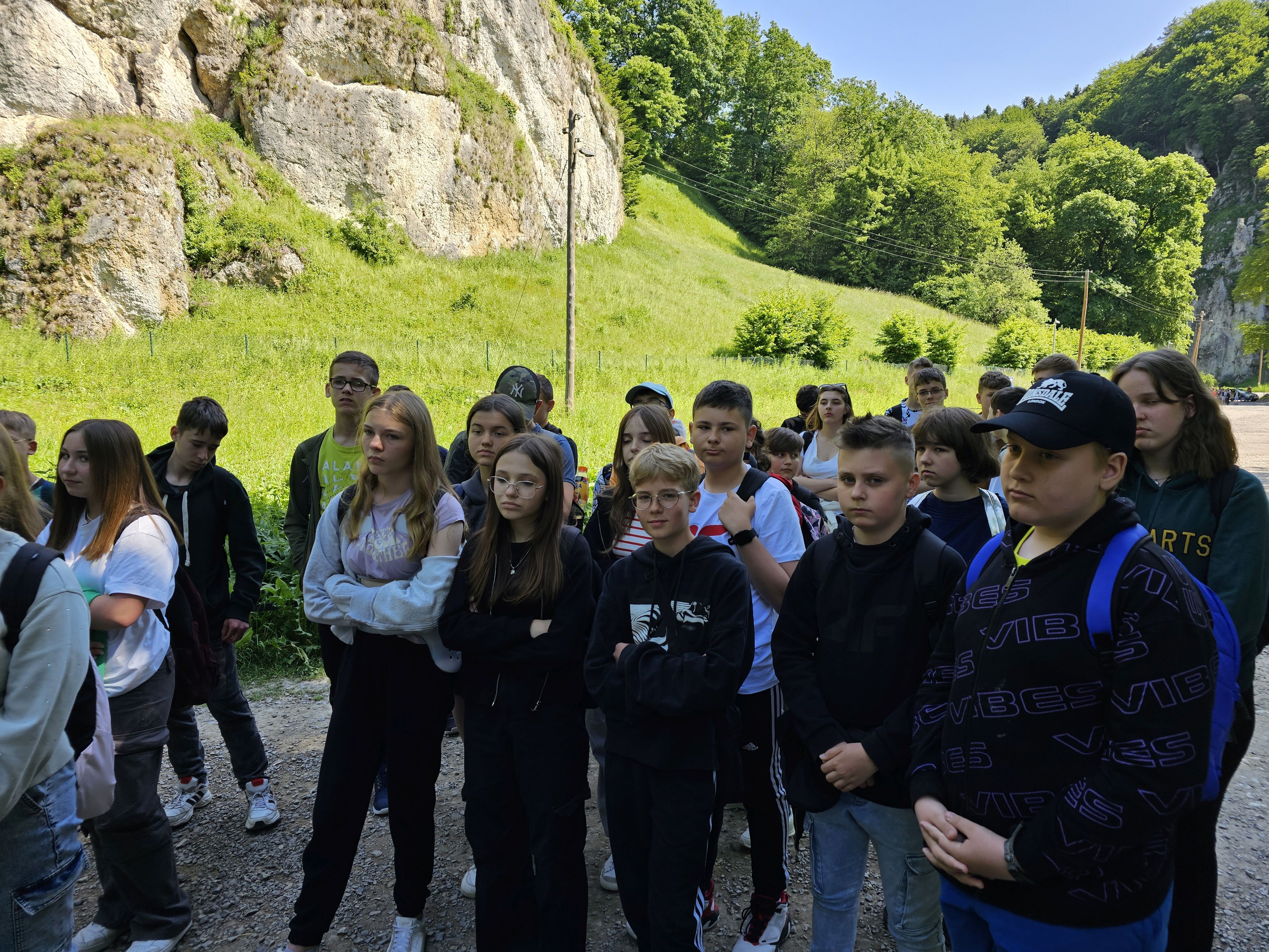 Grupa uczniów słucha przewodnika podczas zwiedzania Ojcowskiego Parku Narodowego