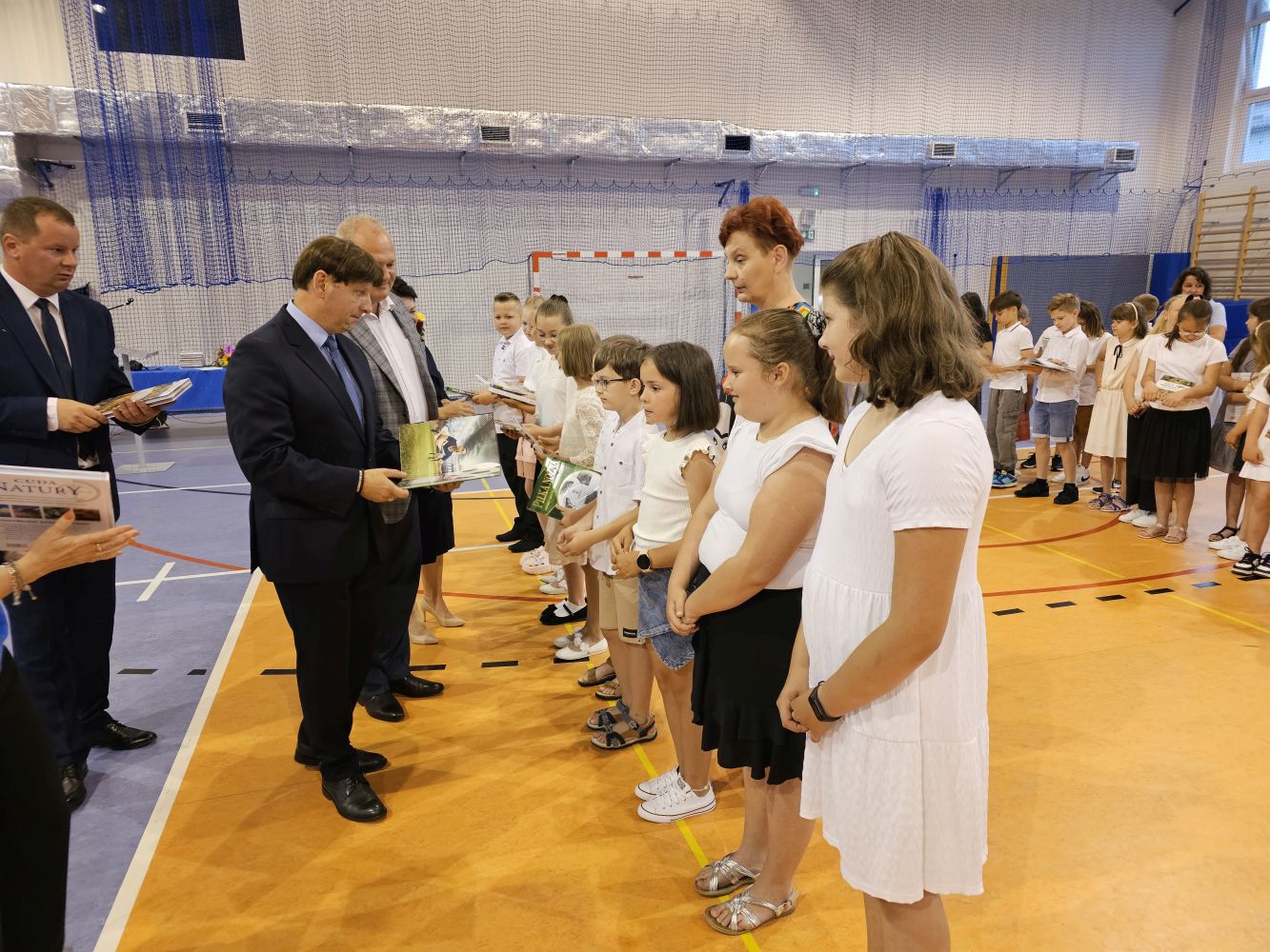 Dyrekcja, zaproszeni goście wręczają uczniom klas trzecich nagrody książkowe