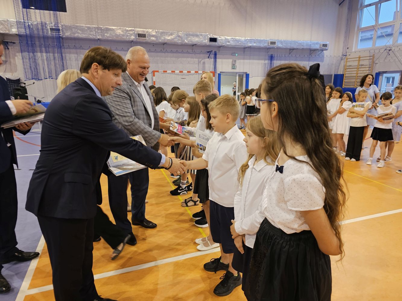 Dyrekcja, zaproszeni goście wręczają uczniom klas trzecich nagrody książkowe