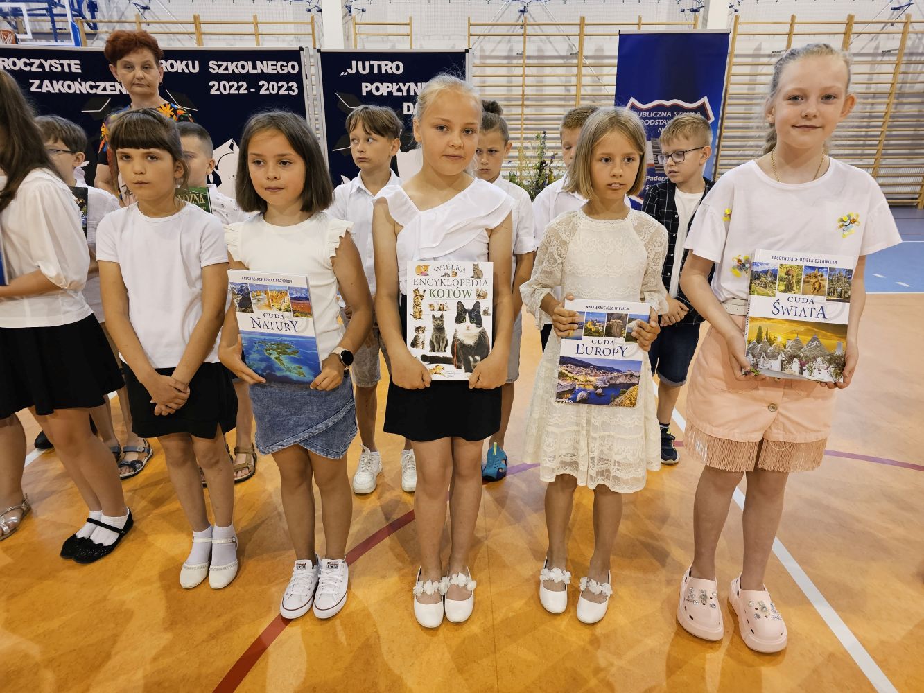 Uczniowie z nagrodami książkowymi, za nimi wychowawczyni